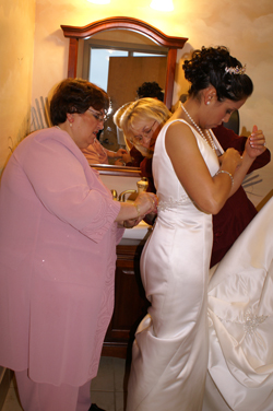 Nina's mother adjusting gown. Mother-in-law looks on.